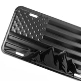 DillenCo embossed aluminum license plate with American flag and mountains for durable outdoor use.