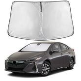 EcoNour windshield shade folded on Prius hatchback, showing compact storage option