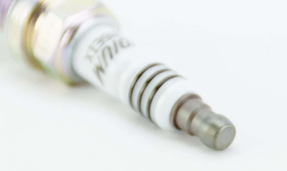 NGK spark plug ground electrode close-up highlighting sharpened spark focus.