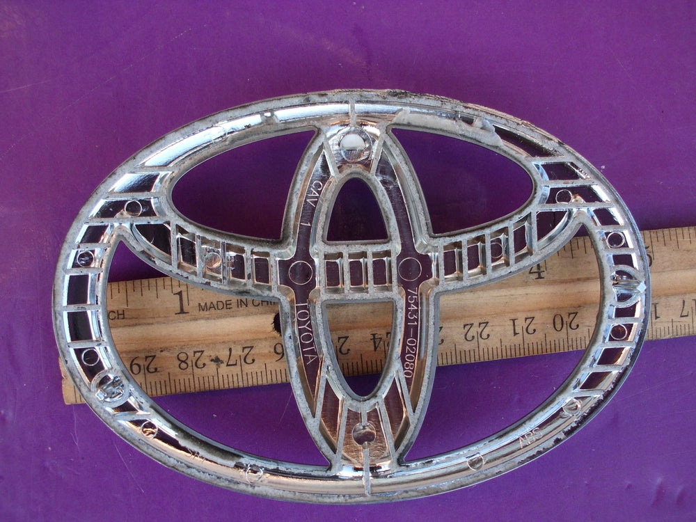 Toyota back-door emblem detail, durable OEM quality for 2008-2011 Camry and Hybrid.