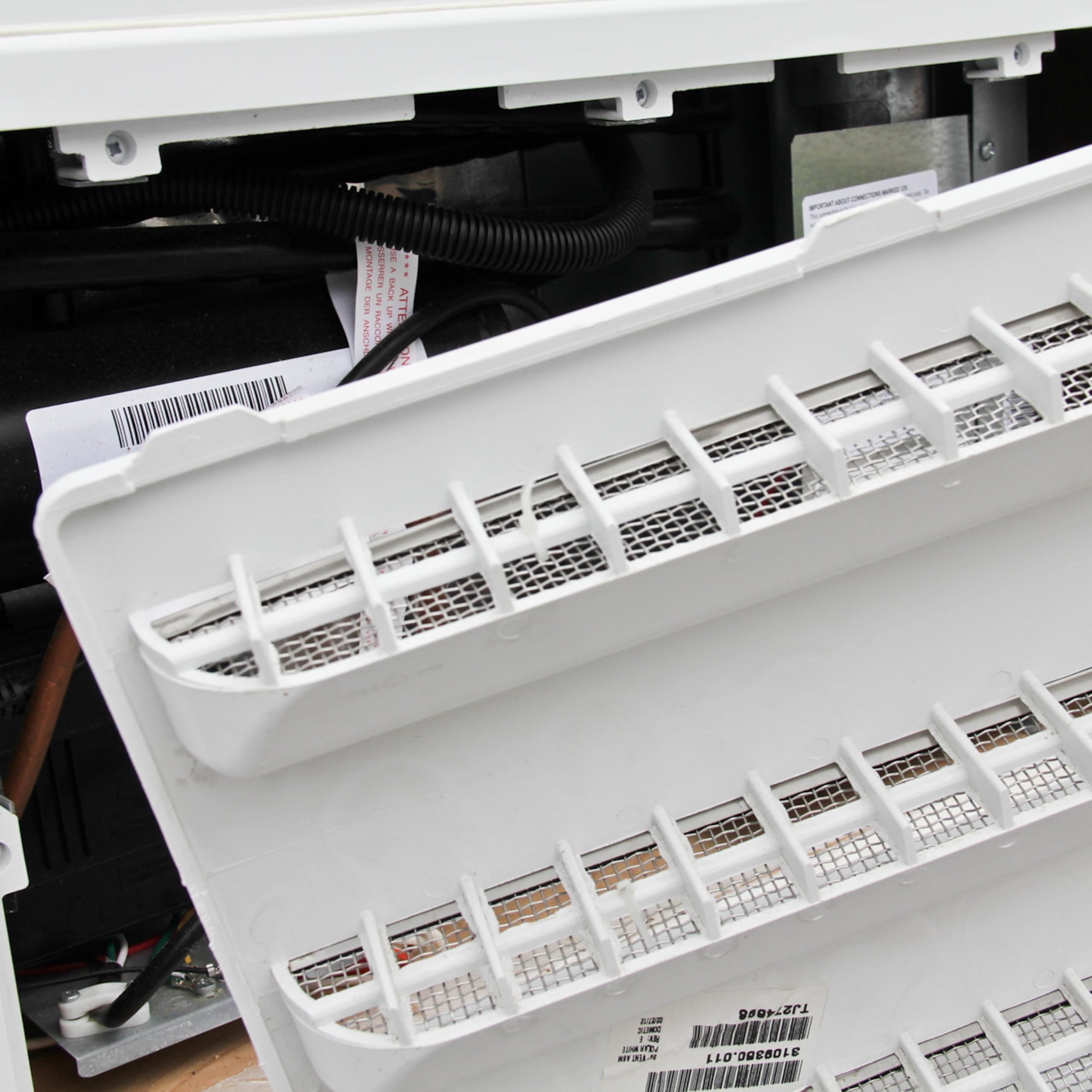 Close-up of screen mesh filtering insects around vent opening.