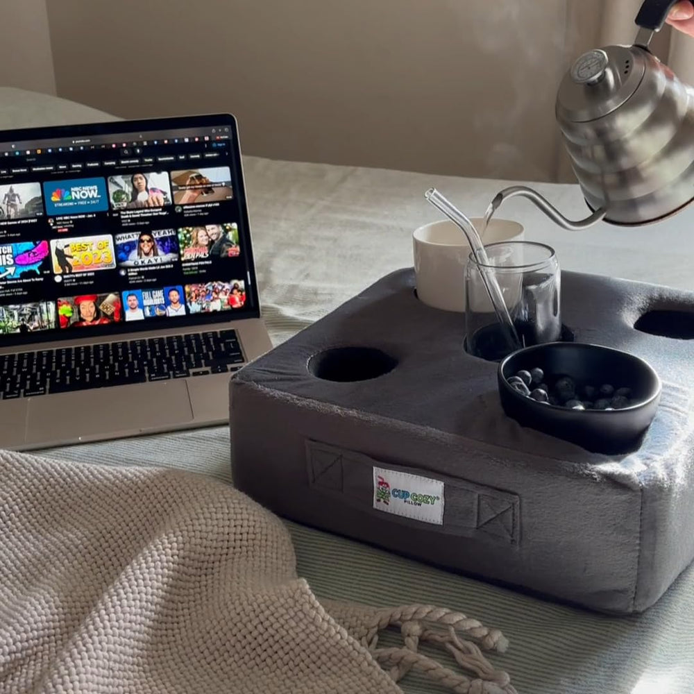 Cup Cozy Deluxe Pillow Gray on bed keeps beverages within easy reach