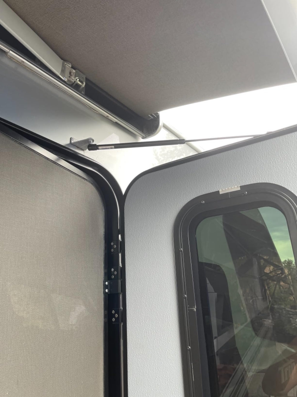 Assembled RV door with strut delivering smooth lift