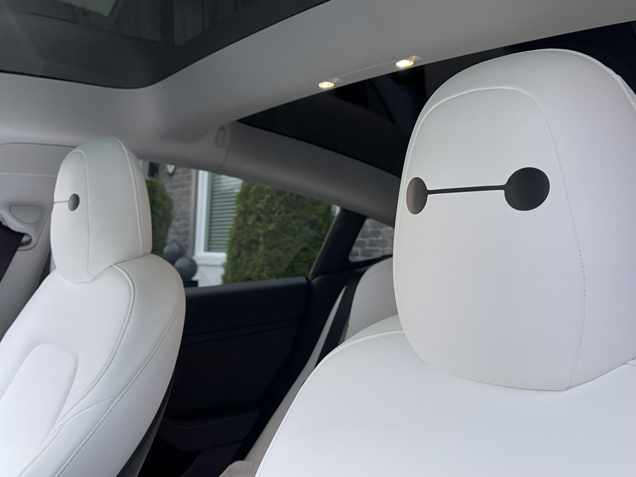 Generic Tesla seat eye decals with Baymax eyes for personal touch in cabin.