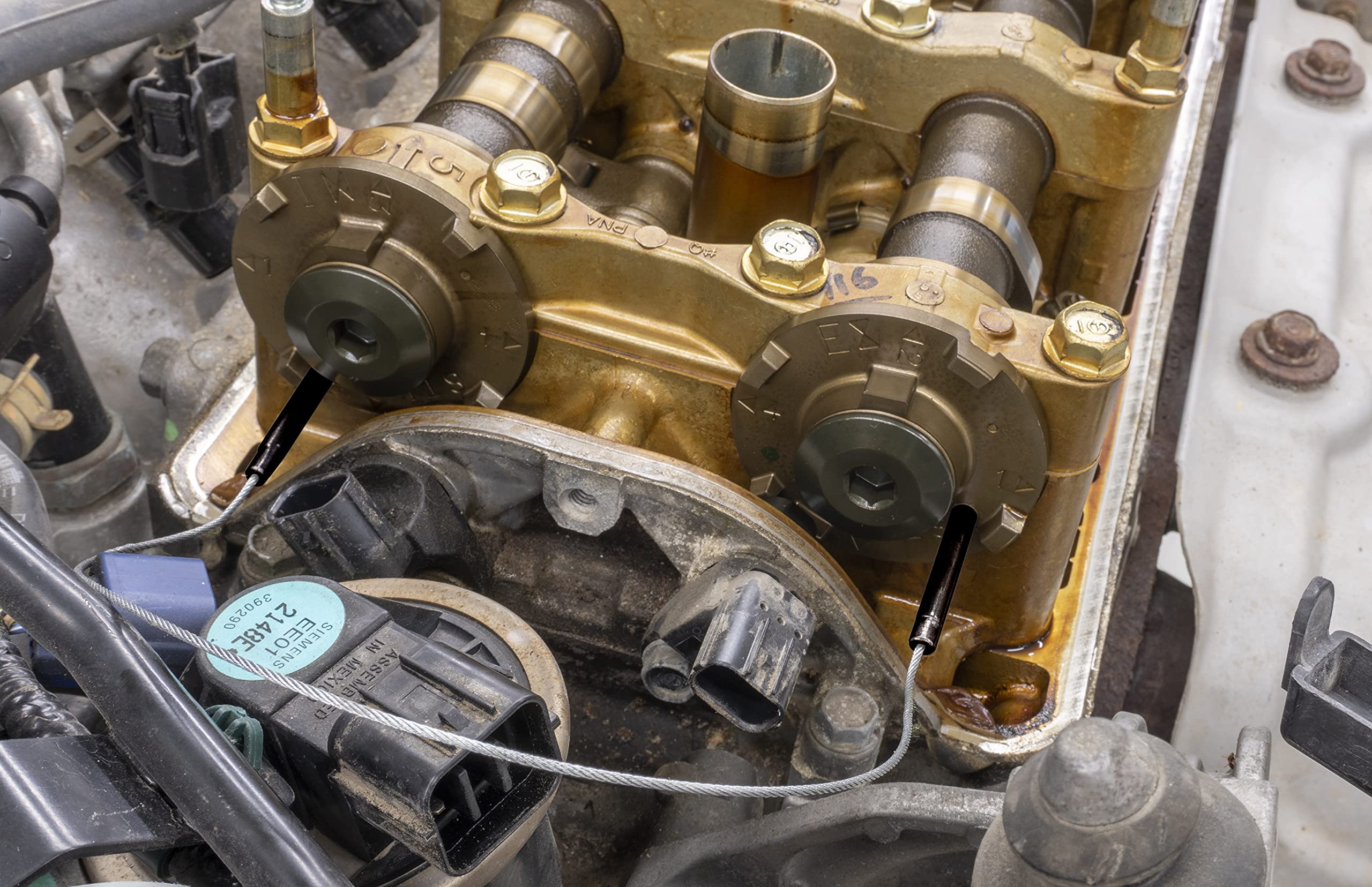 Lisle camshaft lock tool on Honda K-series pulse plates, holding cams for precise timing.