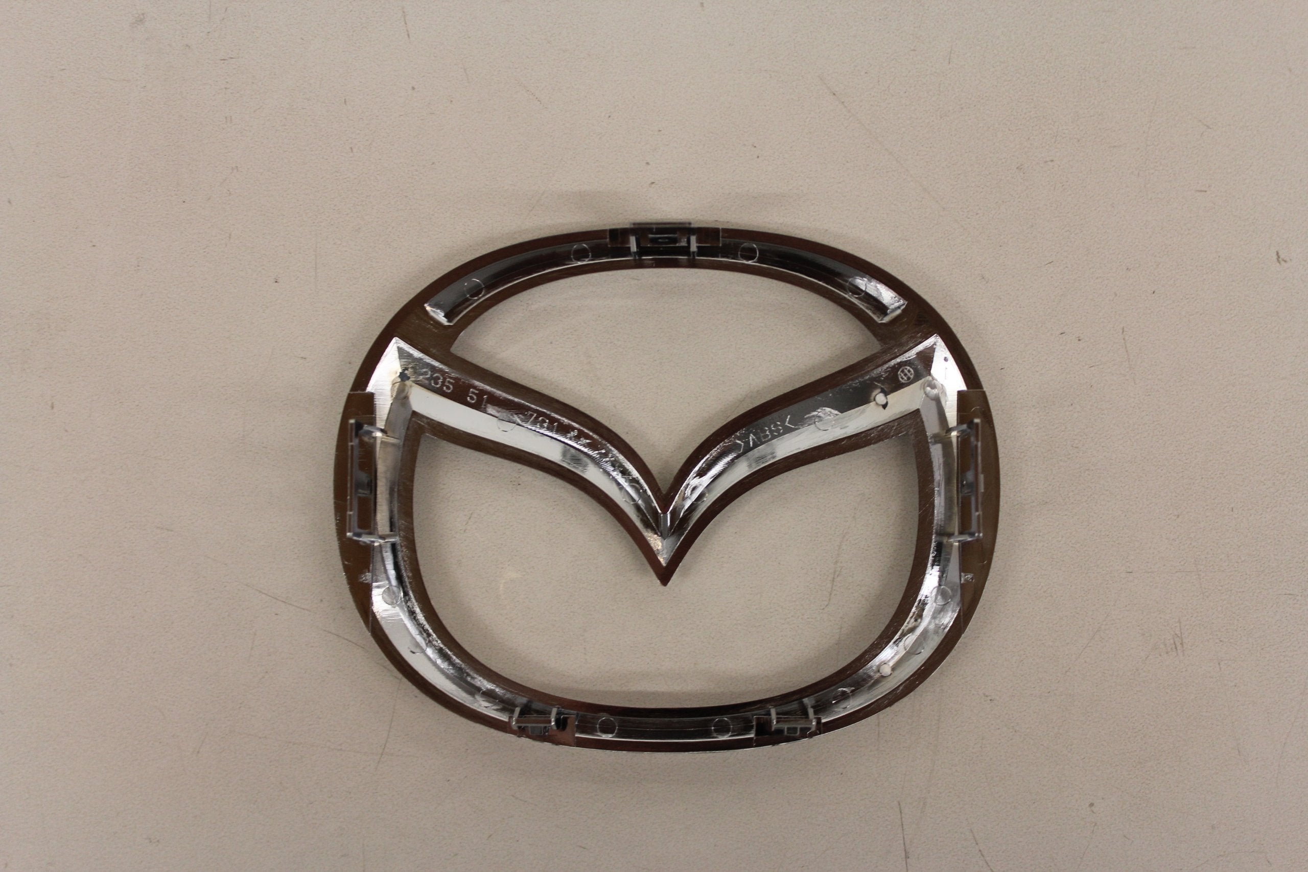 Mazda front logo emblem close-up, durable construction for long-lasting exterior shine.