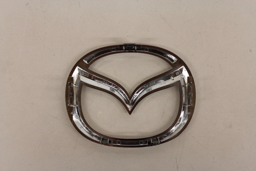Mazda front logo emblem close-up, durable construction for long-lasting exterior shine.