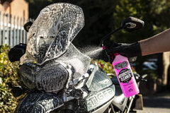 Muc-Off cleaner applied on a bike, lifting grime with a bright pink foam