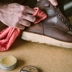 Otter Wax Leather Salve 5oz tin beside leather surface for conditioning protection