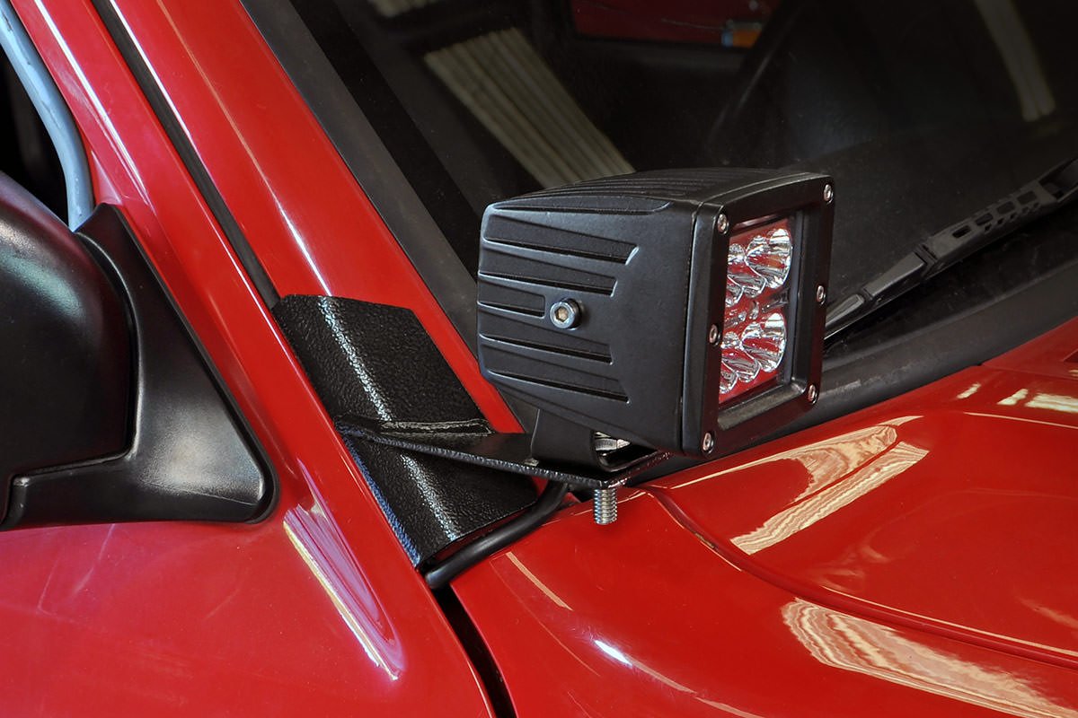 Rough Country lower windshield LED brackets installed on a Jeep Cherokee XJ for improved off-road lighting.